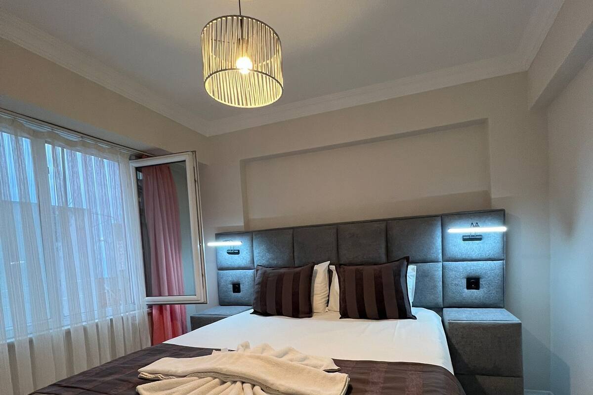 Una habitación de hotel moderna con una cama grande, una mesita de noche y una lámpara del techo.