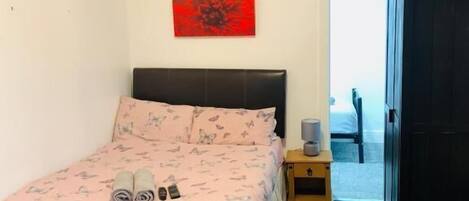 Un dormitorio con cama, una mesita de noche, una obra de arte roja en la pared y un armario.