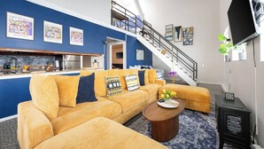 A modern living room with a yellow sofa set, a coffee table, and a staircase leading to an upper level. - Vintage Downtown Penthouse, Safe #6 +gym&balcony (Chicago)