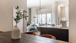 A modern kitchen with a central island, a dining area with a wooden table, and a living room with a sofa and a coffee table. - LUX Dtown Penthouses 9bd/9ba Sleep 25+Parking (Chicago)