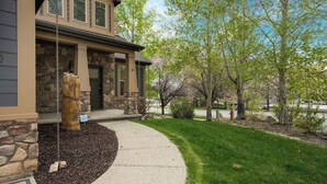 A house with a stone facade, a swing set, and a well-maintained lawn. - Lakeside Haven, a cozy and relaxing home that sleeps 24 with pool/hottub access! (Garden City)