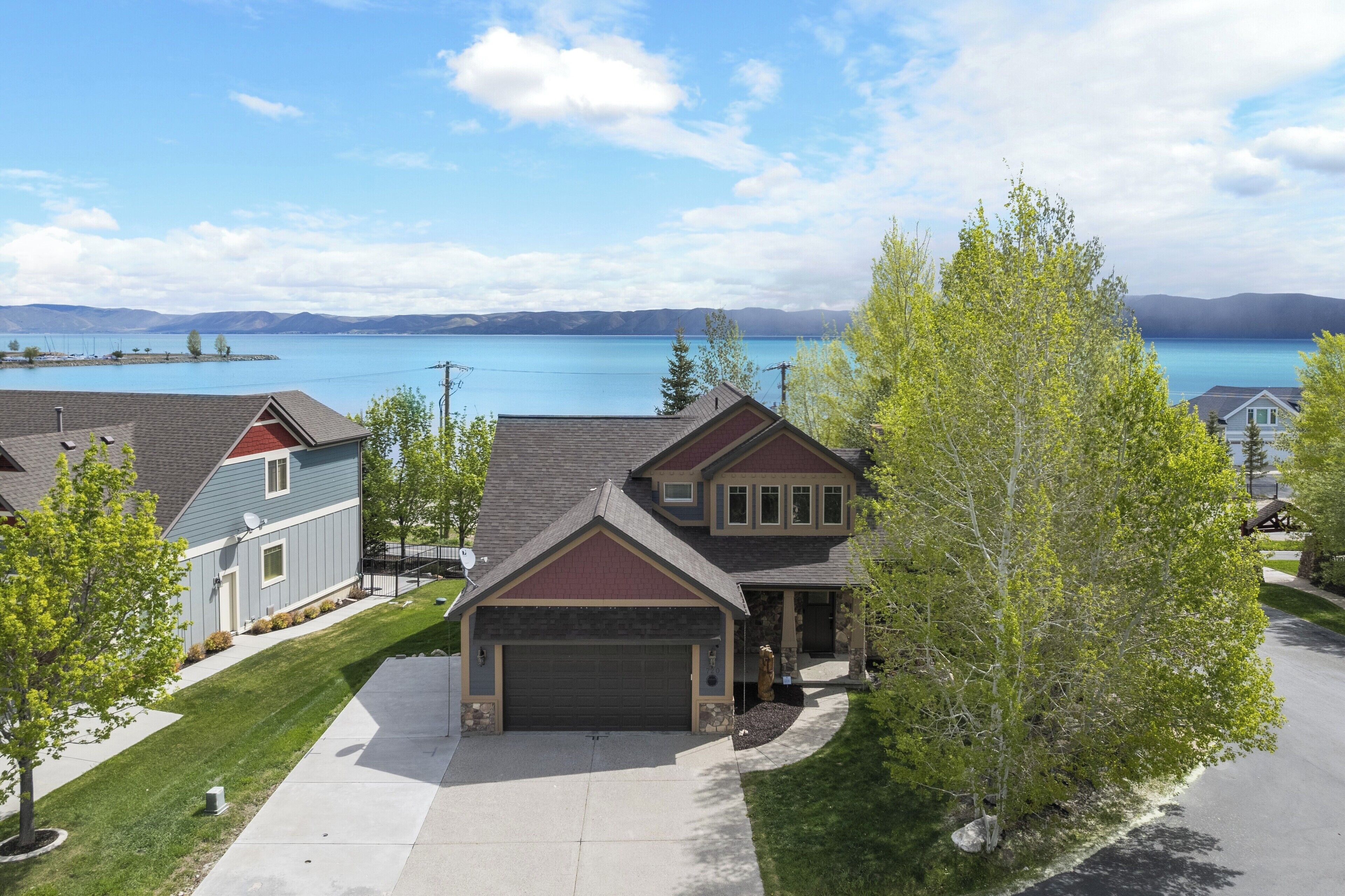 A residential area with houses, a driveway, and a lake in the background.