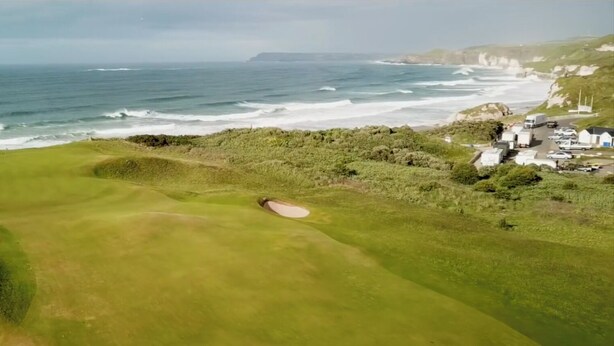 Un campo de golf costero con búnkeres y vista al océano.