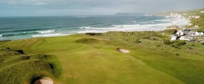 A coastal golf course with bunkers and a view of the ocean.