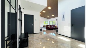 A modern hotel lobby with a polished marble floor, black doors, and a seating area with a leather sofa. - Luxurious 4-room penthouse, roof terrace, parking space, e-charging station (Wachtberg)
