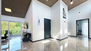A spacious, modern interior with a polished marble floor, a balcony with outdoor furniture, and a large window offering a view of greenery. - Luxurious 4-room penthouse, roof terrace, parking space, e-charging station (Wachtberg)