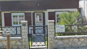 Un bâtiment aux murs de pierre, doté d’un portail en métal, d’une enseigne indiquant « Gîte Halia » et du numéro « 234 » peint sur le mur.