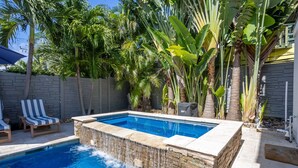A swimming pool with a waterfall feature, surrounded by palm trees and a stone wall. - 2 Side-by-Side Delray Beach Homes & Guest House - 1 blk to beach & Atlantic Ave! (Delray Beach)