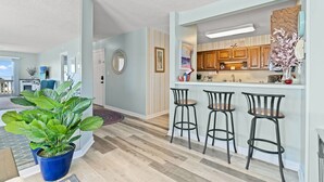 Una cocina moderna con armarios de madera, una barra con taburetes y una planta grande en maceta.