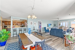 A spacious living area with a dining table, kitchen, and seating area.