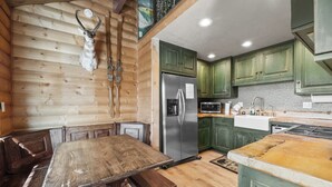 Una cocina rústica con paredes de madera, una mesa de comedor de madera y armarios verdes.