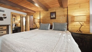 Un dormitorio con paneles de madera, una cama grande, dos mesitas de noche con lámparas y un espejo.