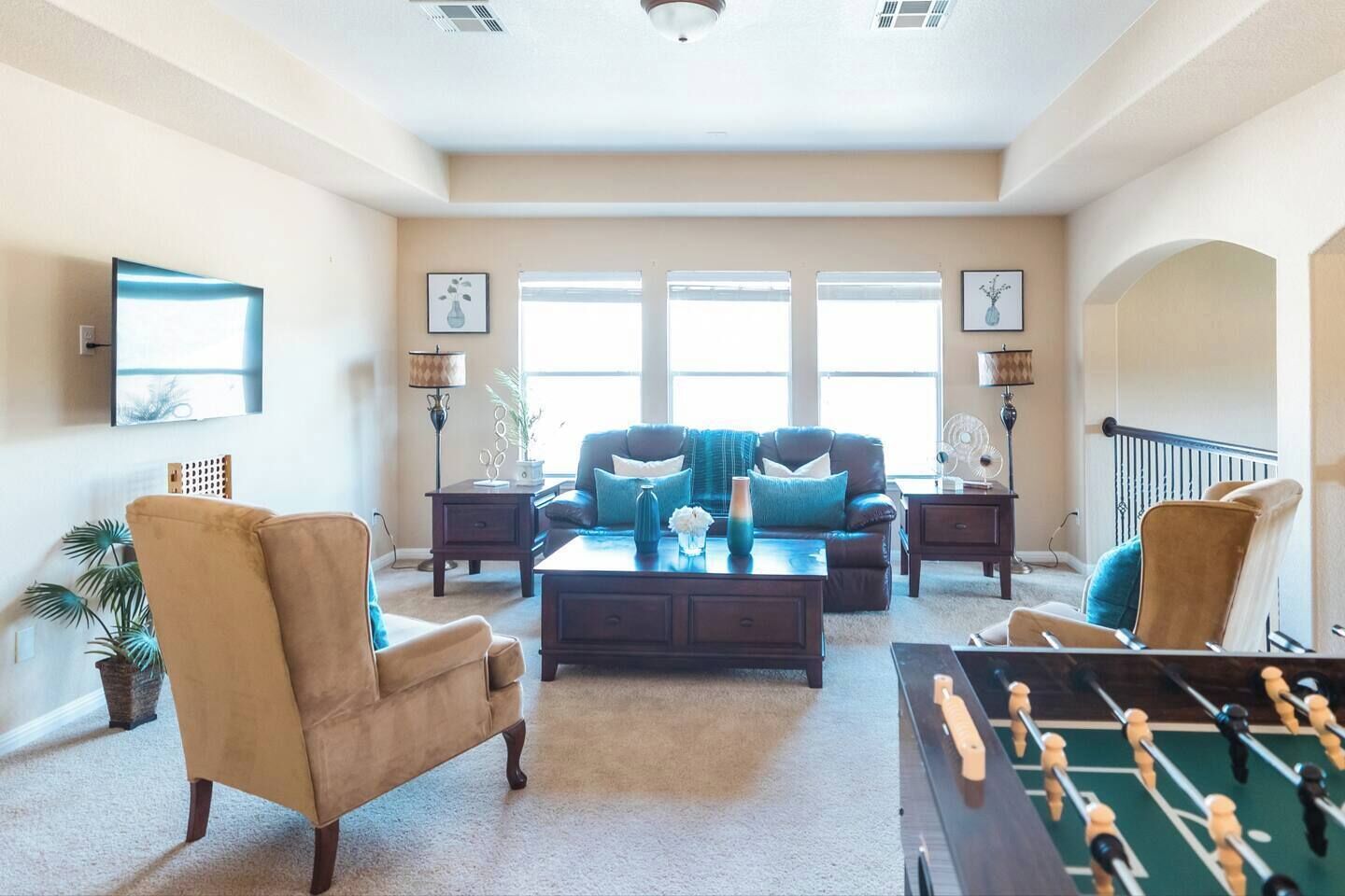 A spacious living room with a sofa set, coffee table, and a foosball table.