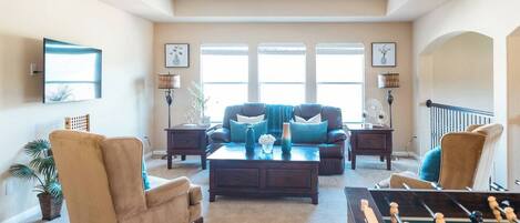 A spacious living room with a sofa set, coffee table, and a foosball table.