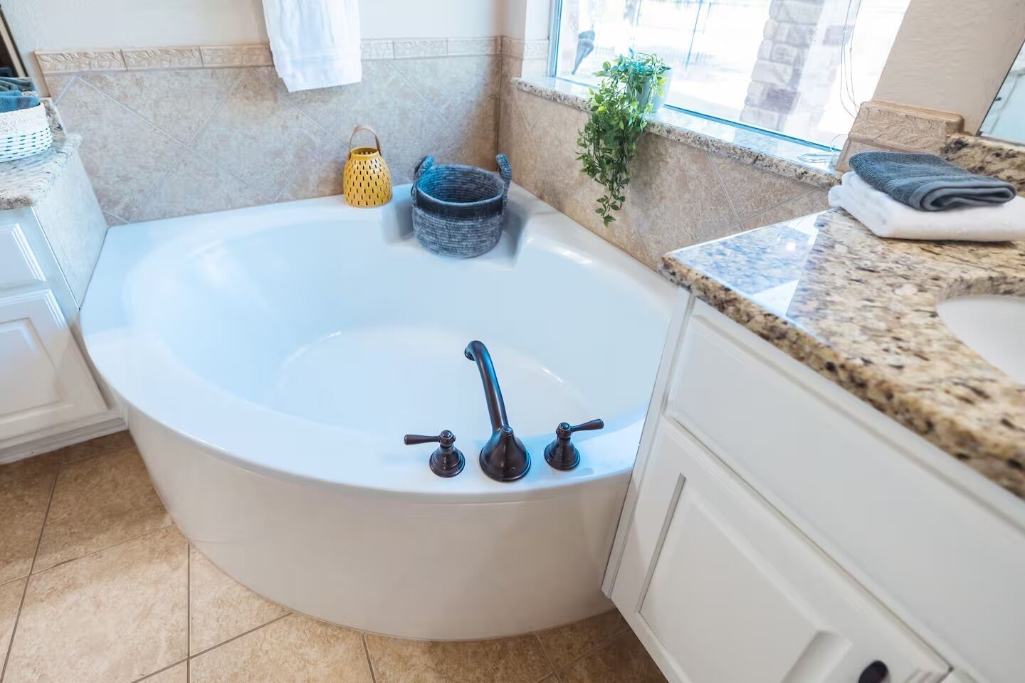 A modern bathroom with a freestanding bathtub, a granite countertop, and a potted plant.