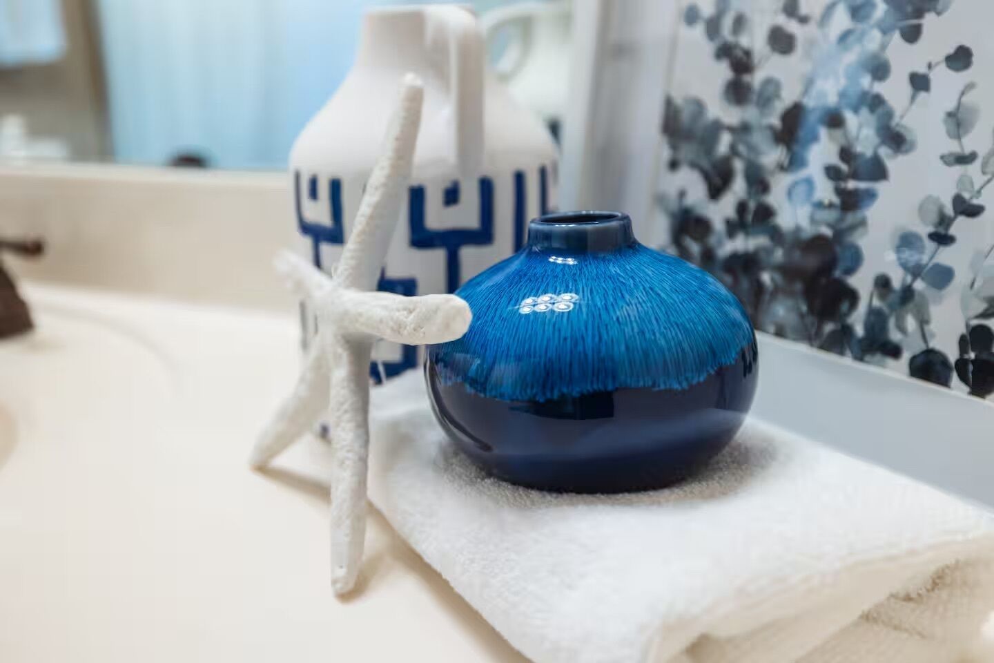 A blue vase with a textured blue top and a white starfish decoration on a white towel.