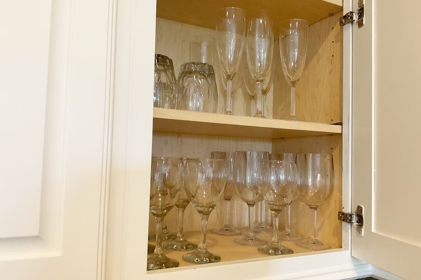 A cabinet with two shelves filled with wine glasses.