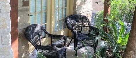 Two wicker chairs outside a stone building with a window.