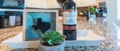 A bottle of Castillo San Simon Tempranillo wine on a white tray with a framed map of Texas and a succulent plant.