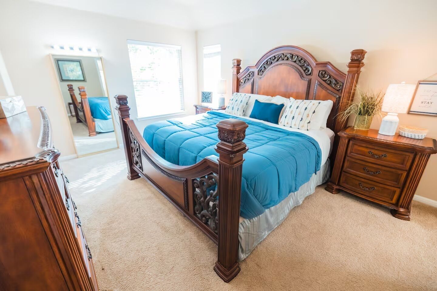 A bedroom with a large bed, a wooden nightstand, and a dresser.