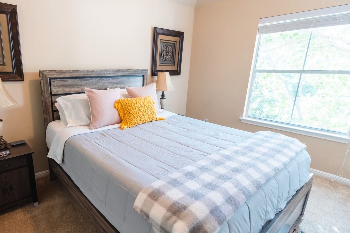 A bedroom with a bed, a nightstand, a lamp, and a window.