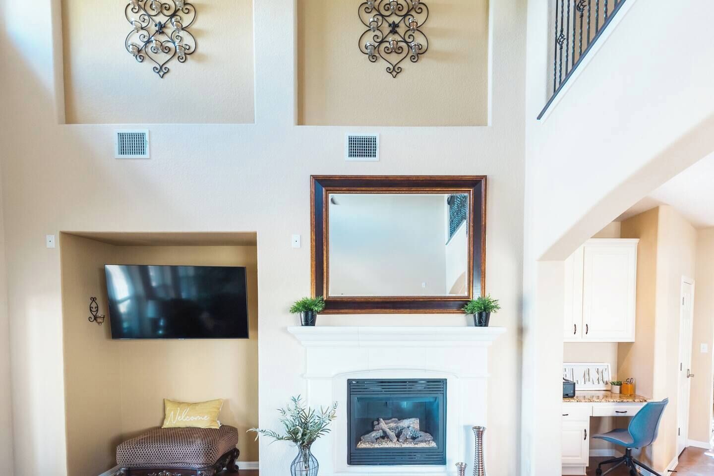 Una sala de estar con chimenea, televisor montado, apliques decorativos y una escalera.
