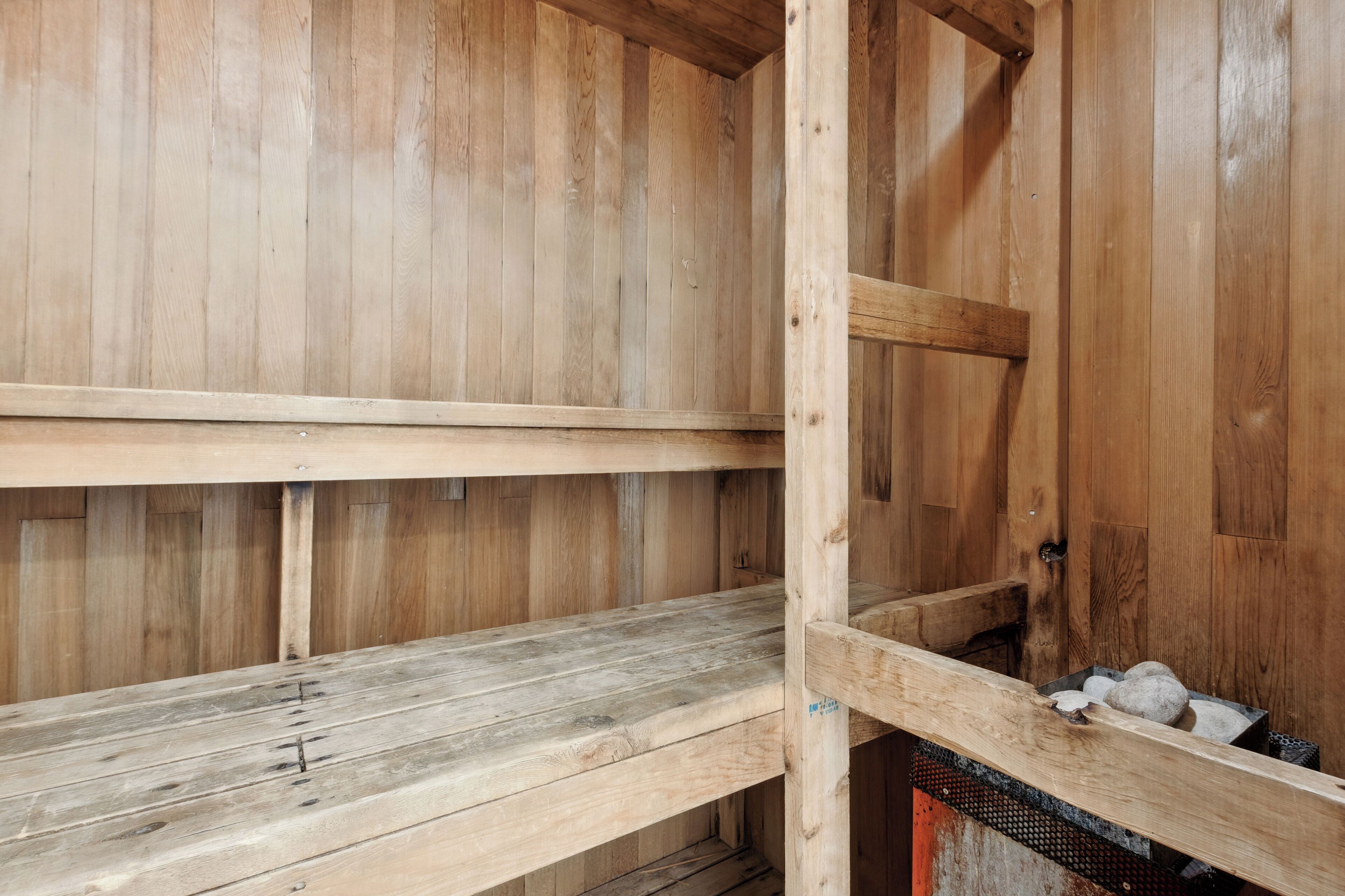 A wooden interior with two wooden benches and a metal rack.
