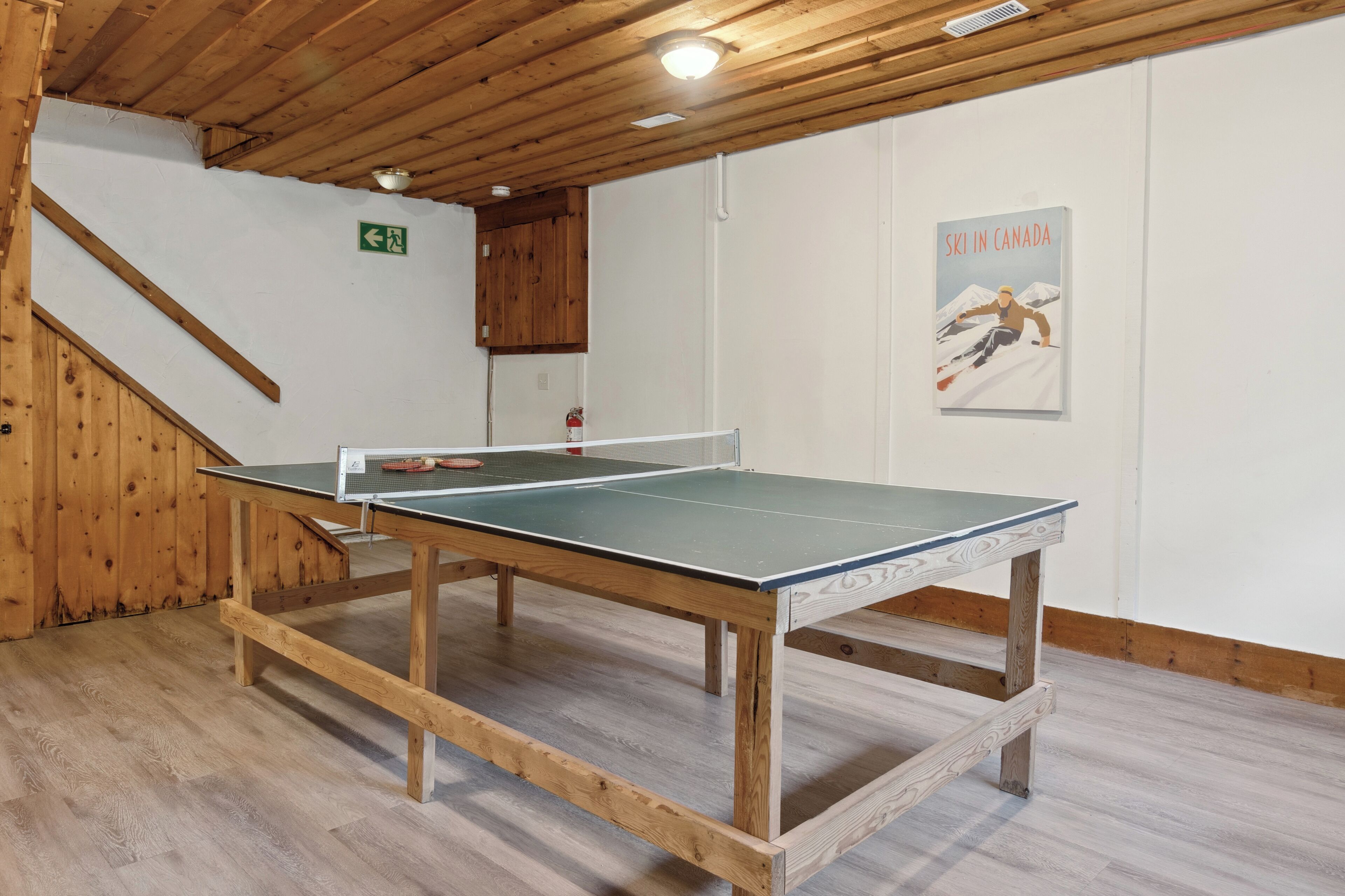Een tafeltennistafel in een ruimte met houten vloer en een houten plafond.