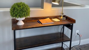 Ein Holzkonsolentisch mit einer Topfpflanze, einer Lampe und einem Notizbuch.