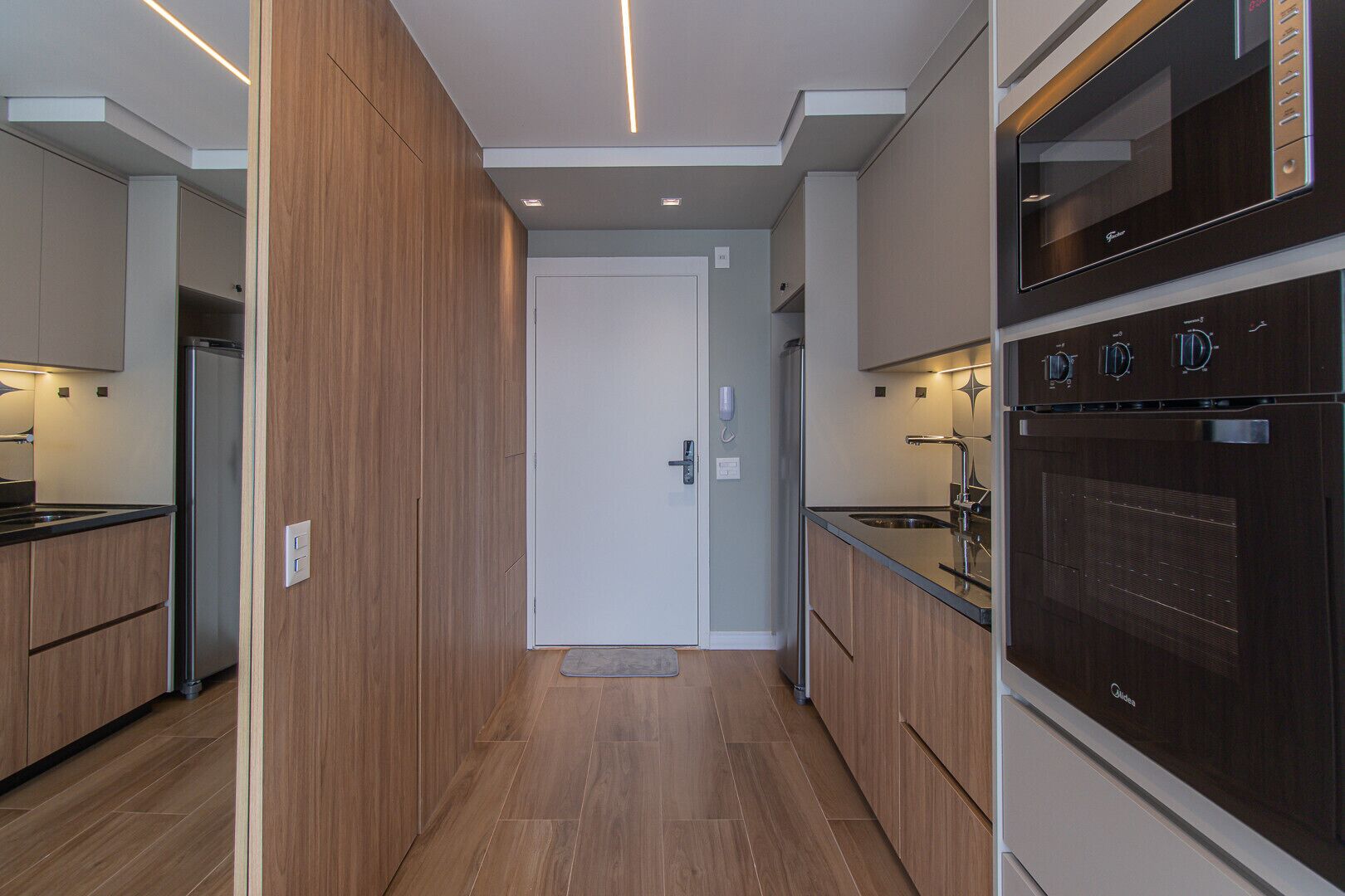 Une cuisine moderne dotée de meubles en bois, d’appareils électroménagers en acier inoxydable et d’un four encastré.