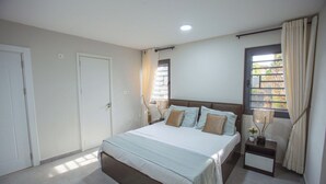 Une chambre à coucher avec un lit, des tables de chevet, une fenêtre avec des rideaux et une porte.