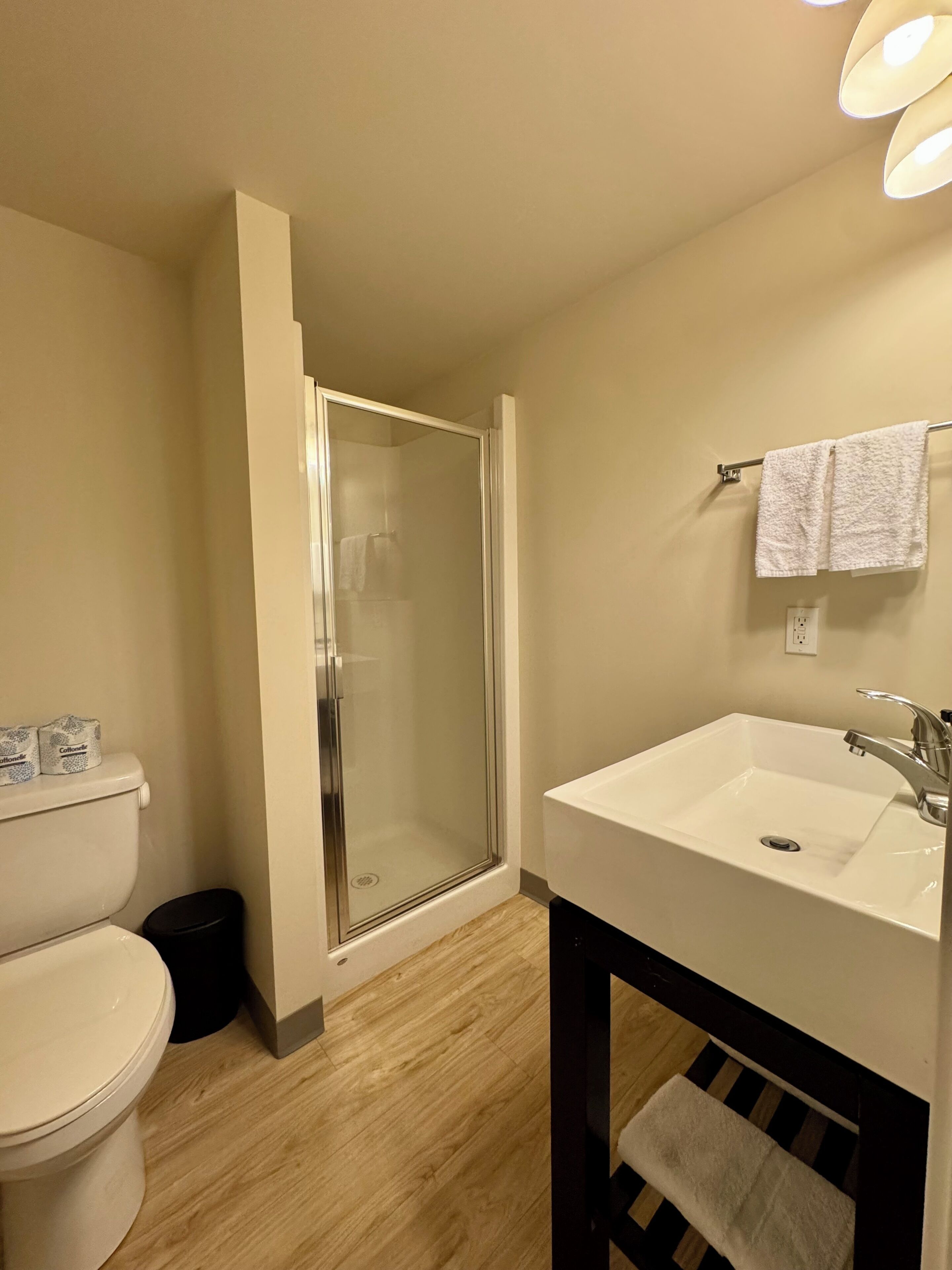 A bathroom with a toilet, a shower enclosure, a sink, and a towel rack.