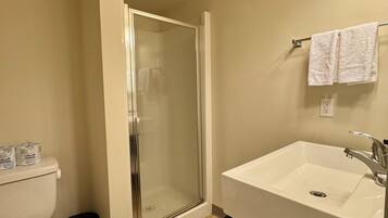 A bathroom with a toilet, a shower enclosure, a sink, and a towel rack.