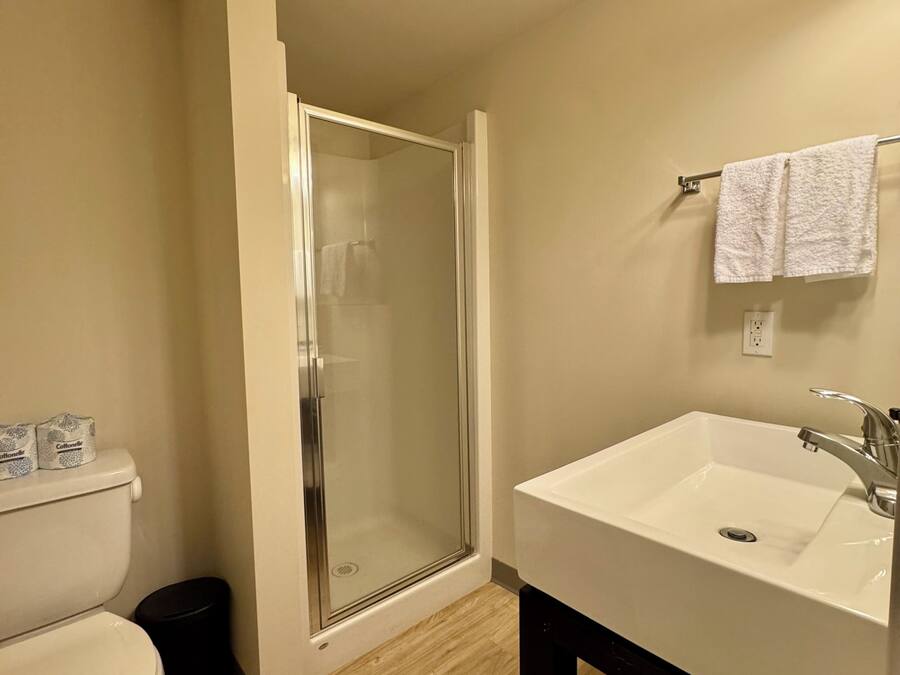 A bathroom with a toilet, a shower enclosure, a sink, and a towel rack.
