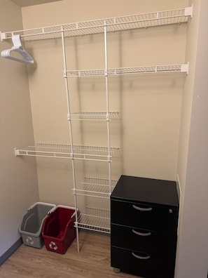 A storage closet with metal shelves, a black filing cabinet, and two recycling bins. - The Lodges Capilano University Squamish (Squamish)