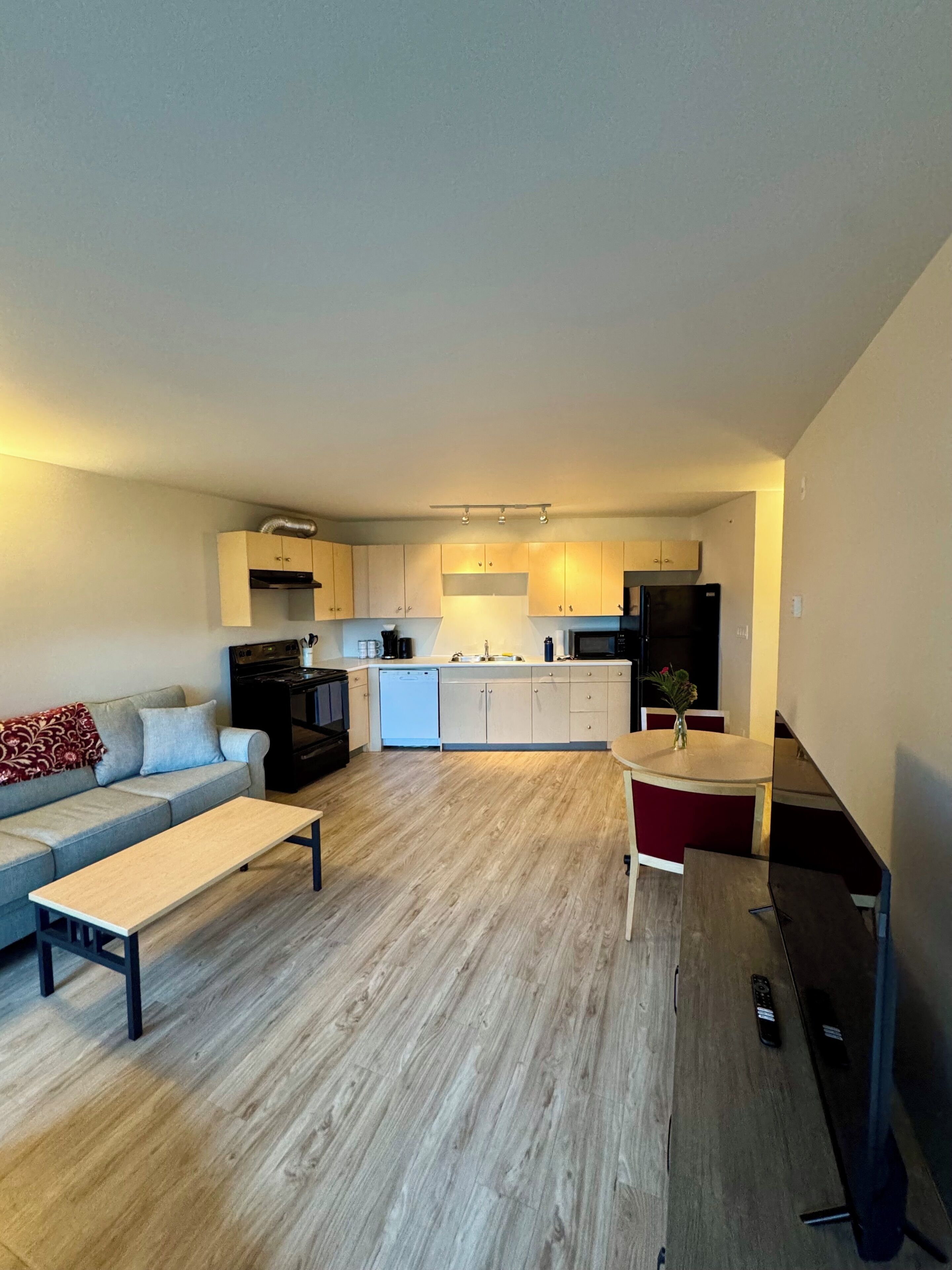 A modern kitchen with a dining area, a sofa, and a coffee table.