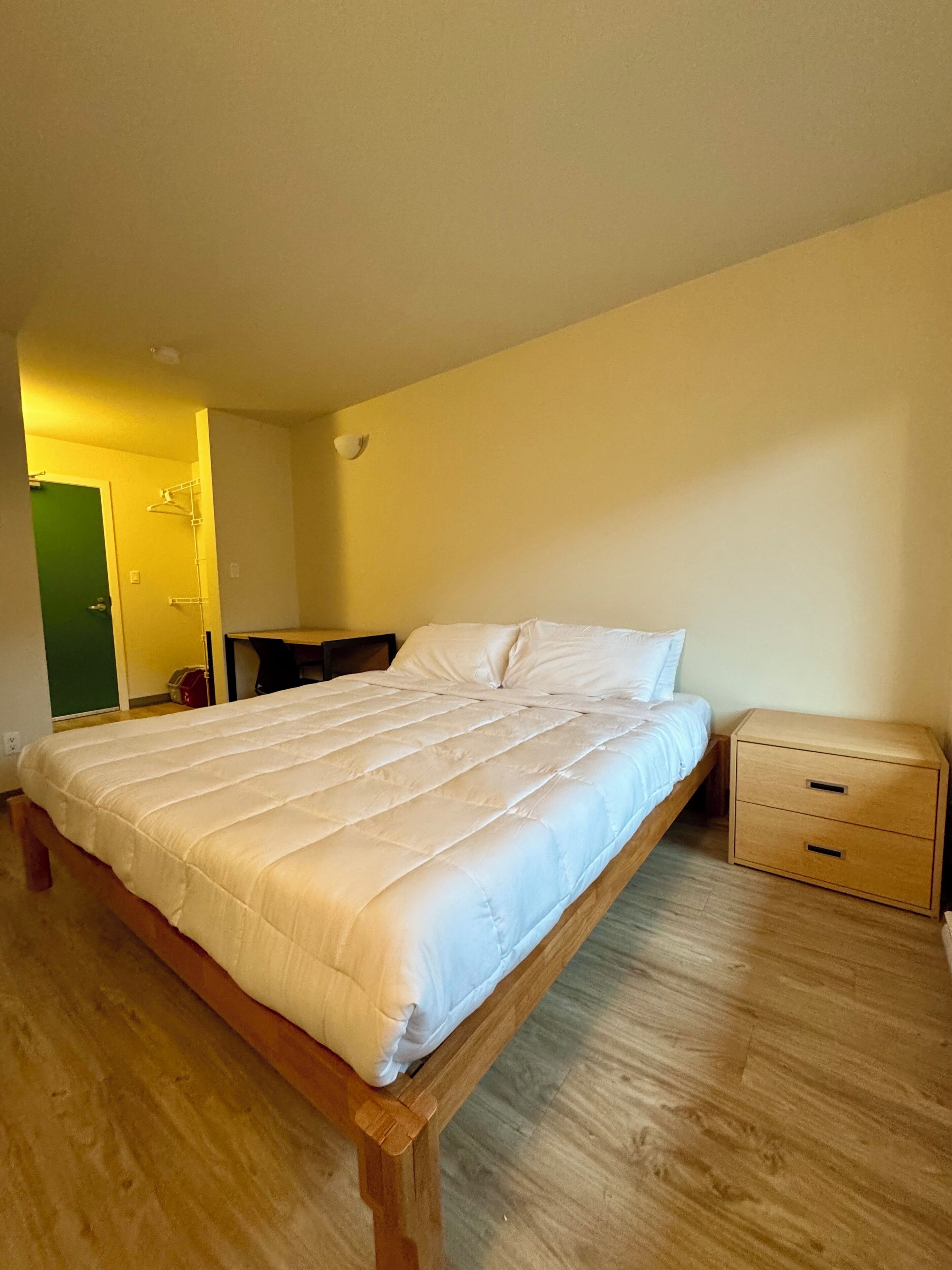 Un dormitorio con una cama de madera, una mesita de noche y una cómoda pequeña.