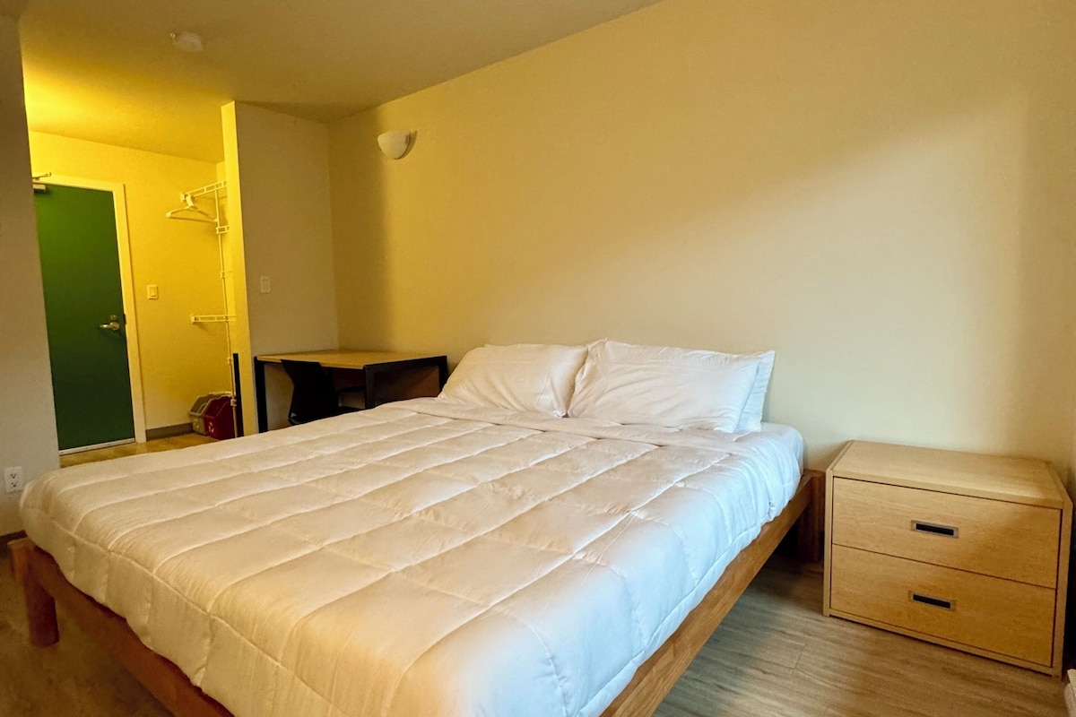 A bedroom with a wooden bed, a bedside table, and a small drawer unit.