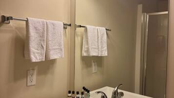 A bathroom with a large mirror, white sink, and three overhead lights.