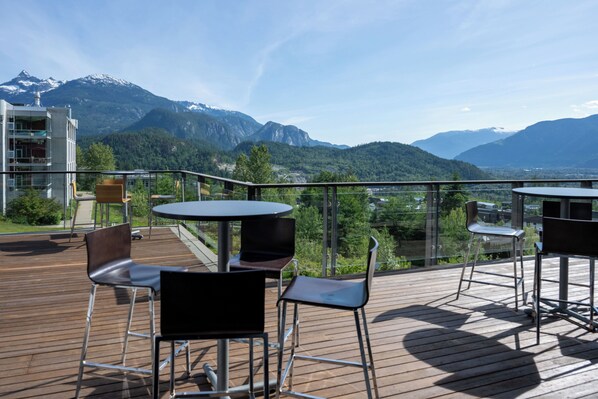 A deck with outdoor seating, overlooking a mountainous landscape.