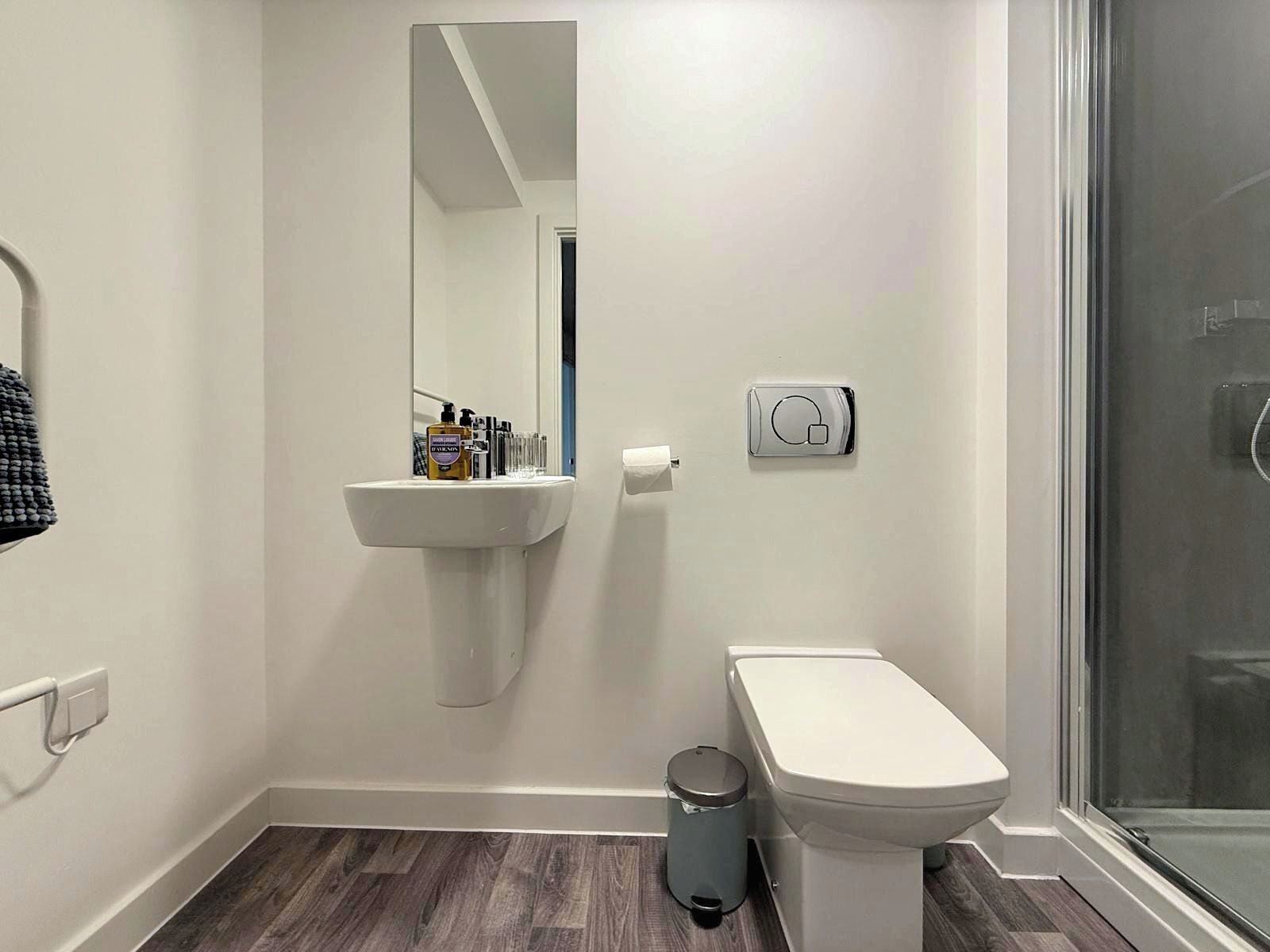 A modern bathroom with a white sink, toilet, and a glass shower enclosure.