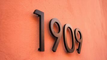 Un letrero adherido a la pared con los números "1909" en una tipografía metálica y moderna.