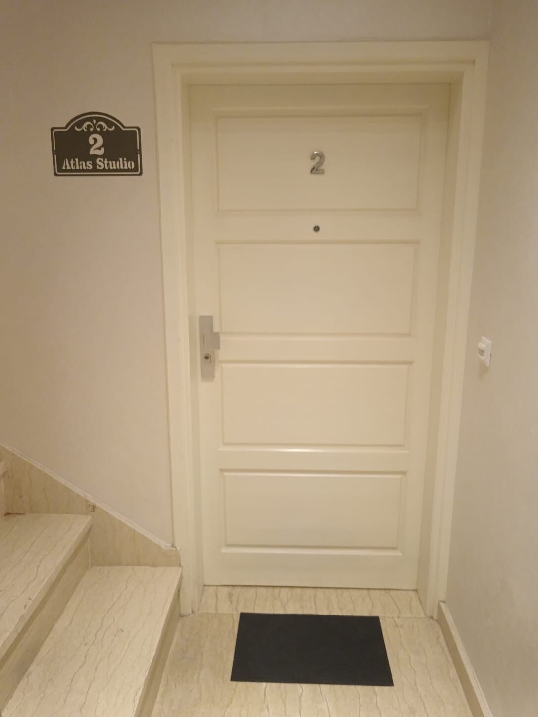 Una puerta blanca con el número 2 y un cartel que dice 'Atlas Studio'.