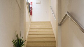 A staircase with a handrail, a potted plant, and a fire extinguisher in the background. - Family Stay Ouarzazate (Ouarzazate)