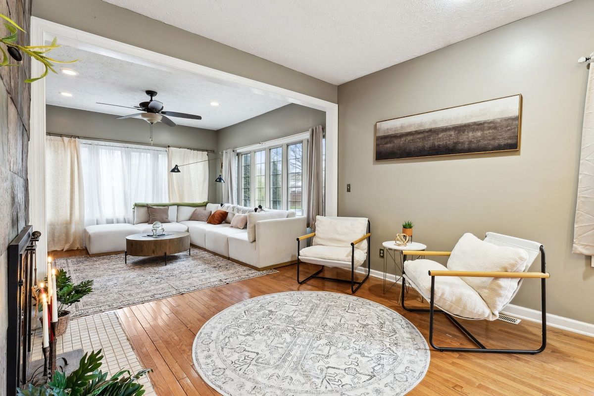 Een moderne woonkamer met een bank, fauteuils, een salontafel en een groot vloerkleed.