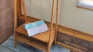 Een houten schommelstoel met een plank, geplaatst tegen een muur met een raam.