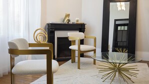 Una sala de estar moderna con una mesa de centro de vidrio, dos sillones, una chimenea y un espejo grande.
