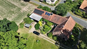 A house with a solar panel roof, surrounded by a well-maintained garden and a field.