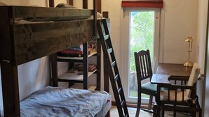 A room with a bunk bed, a desk, a chair, and a window.