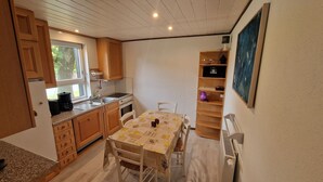 A compact kitchen with wooden cabinets, a built-in oven, and a dining table with chairs.